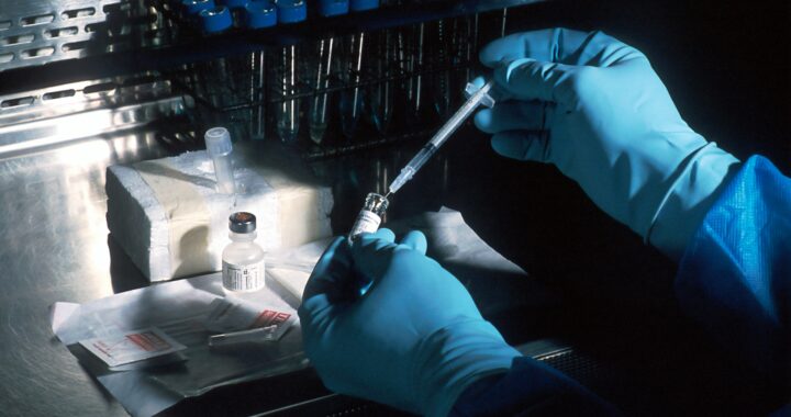 A scientist looking at a sample through a microscope